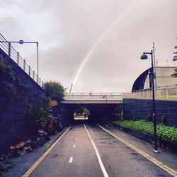 Rainbow over road against sky