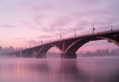 Arch bridge over river against sky during sunset