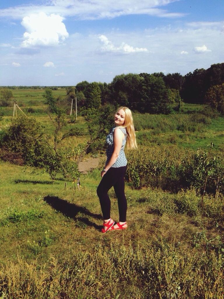 WOMAN WALKING ON FIELD AGAINST SKY