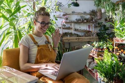 Young woman waving while video conferencing over laptop at home