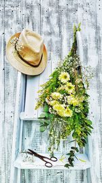 Flowers and hat on ladder against wooden wall