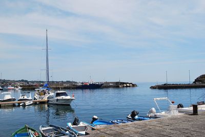 Boats moored at harbor against sky