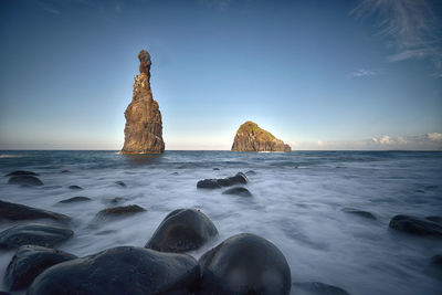 Rock formation on beach against sky