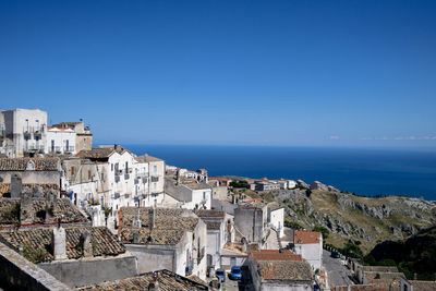 High angle view of townscape by sea against clear blue sky