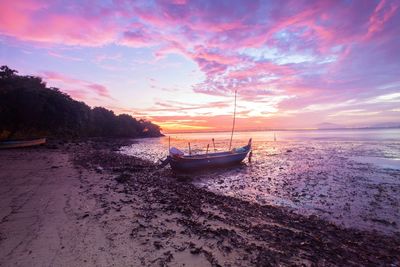 Boat moored on sea against sky during sunset