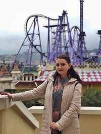 Portrait of smiling young woman standing against built structure