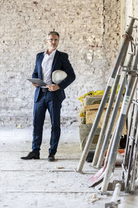 Full length portrait of young man standing against wall