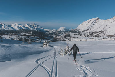 People skiing on snow covered mountain against sky