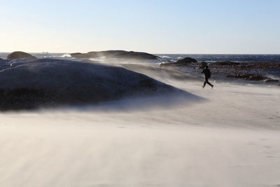 Person running on beach against clear sky