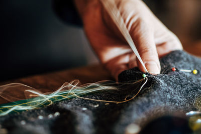 Close-up of cropped hand sewing textile in workshop