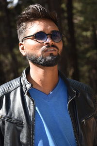 Portrait of young man wearing sunglasses standing in forest