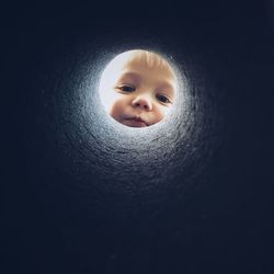 Low angle portrait of child peeking in pipe