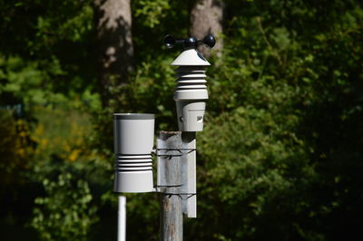 Close-up of security camera against trees