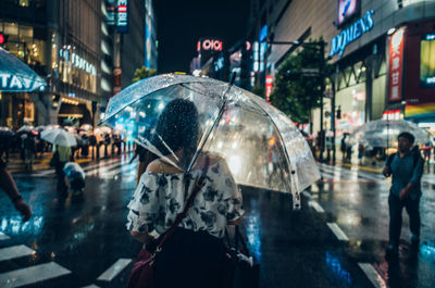 Rear view of people walking on wet street during rainy season