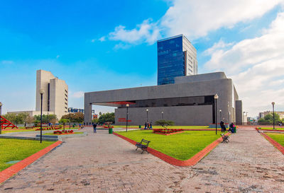 Footpath by modern buildings against sky in city