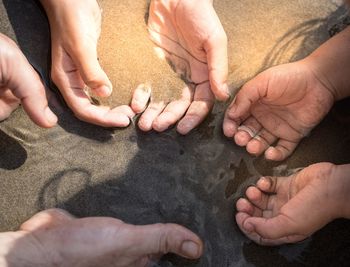 High angle view of people hands on sand