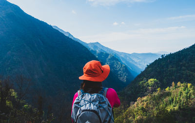 Rear view of woman looking at mountains against sky