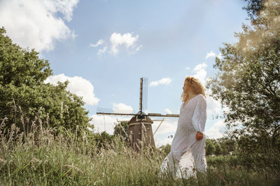 Rear view of pregnant woman standing on field