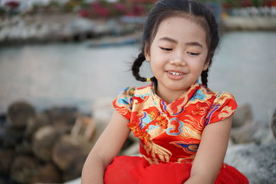 Smiling girl looking away while sitting on rocks