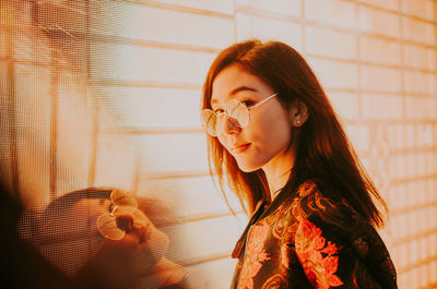 Portrait of young woman standing against illuminated city at night