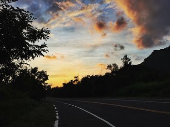 Empty road against cloudy sky at sunset