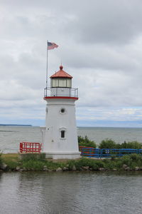 Lighthouse by sea against sky