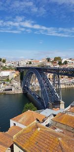 Arch bridge over river in city against sky