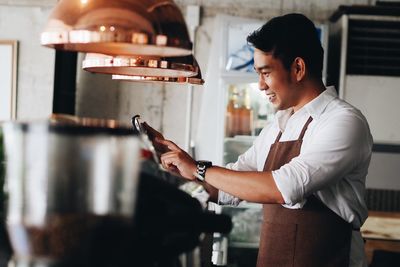 Side view of chef using mobile phone