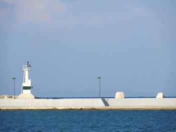 Lighthouse by sea against clear sky