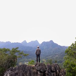 Rear view of man looking at mountains against sky