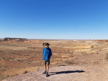 Full length of boy walking on landscape against clear blue sky