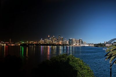 Distant view of illuminated city by sydney harbour at night