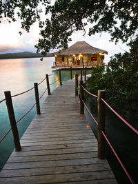 Wooden pier leading towards lake against sky