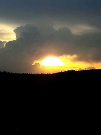 Scenic view of silhouette landscape against dramatic sky during sunset