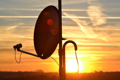 Close-up of silhouette telephone against orange sky