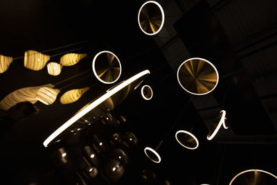 Low angle view of illuminated lighting equipment against black background