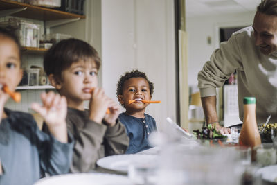 Multiracial male and female students eating carrots for breakfast in day care center