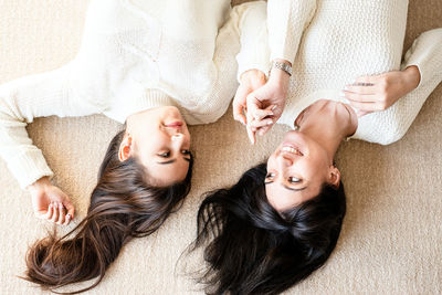 Two best friends laying on the rug at home talking, top view