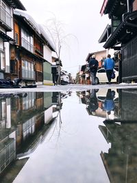 People walking on road by buildings against sky