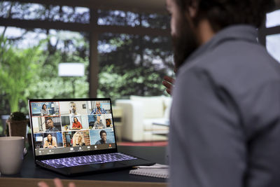 Rear view of man using laptop at table