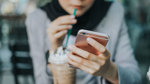 Midsection of woman using mobile phone at cafe