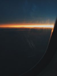 Aerial view of airplane wing against sky during sunset