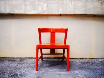 Empty red chair against retaining wall