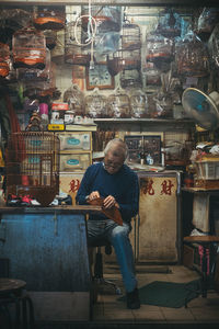 Full length of man making birdcage at store