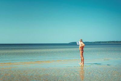 Man standing on beach against clear sky