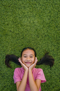 Portrait of smiling girl lying on grassy field