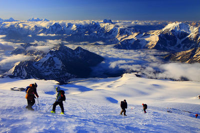 Hikers on snowcapped mountains against sky