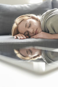 Young woman sleeping on sofa by digital tablet on table
