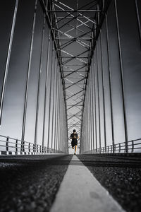 Man running on bridge against sky