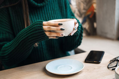 Midsection of woman using mobile phone on table